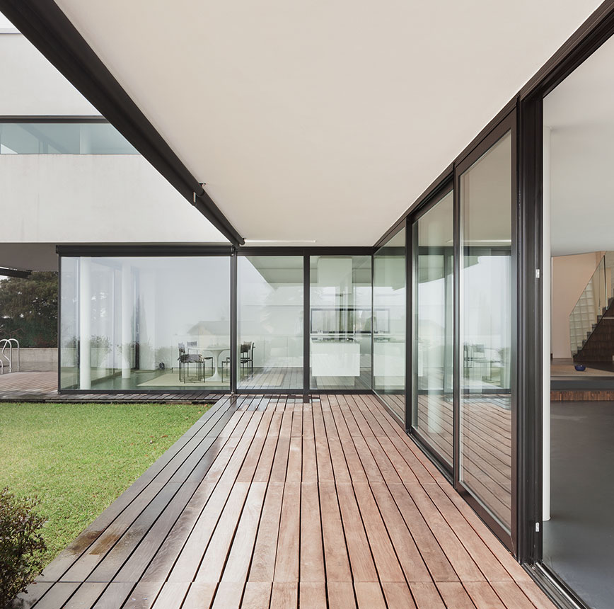 Casa moderna con ampie vetrate scorrevoli, pavimento in legno e giardino, dal design minimalista e dalle linee essenziali.