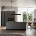 Cucina moderna Arredo 3 con isola, mobili grigi, sgabelli marroni, elettrodomestici e pavimento in legno.