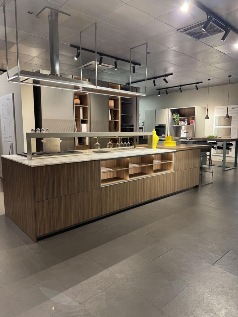 Ampio allestimento cucina con isola centrale, colonne in legno e cappa sospesa
