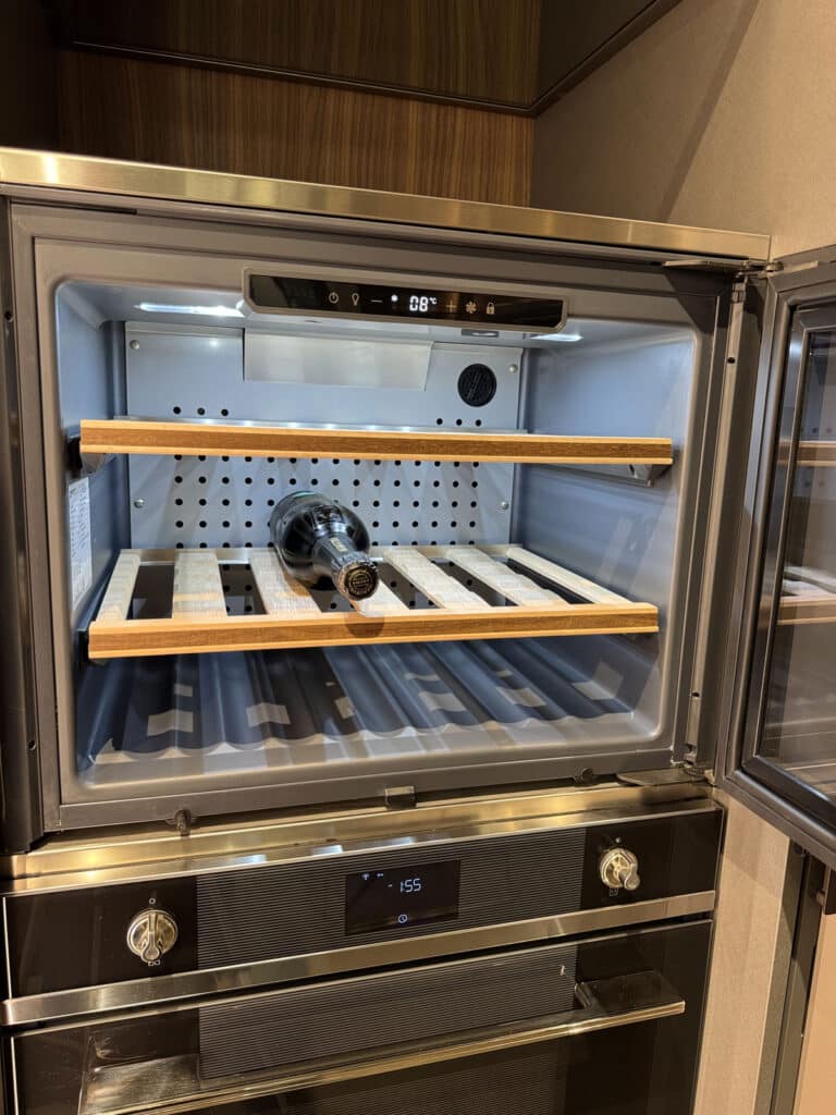 Cantinetta per vini aperta con ripiani in legno, incassata in una colonna cucina