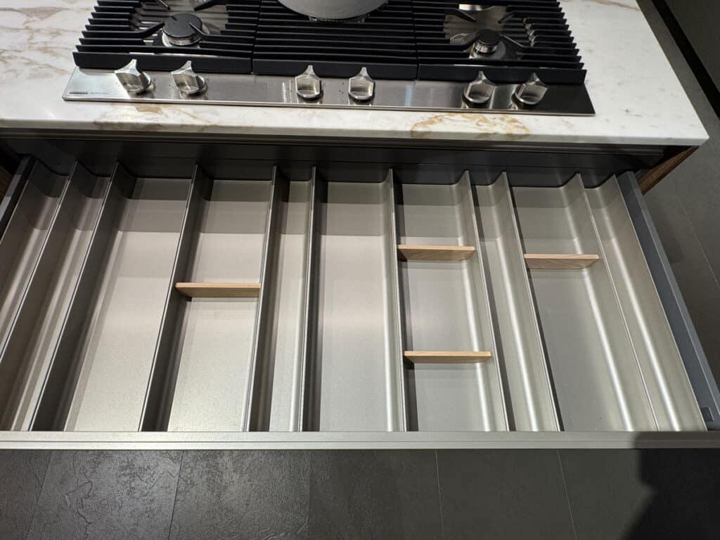Cassetto attrezzato aperto con divisori sotto il piano cottura di una cucina Ernestomeda Sign