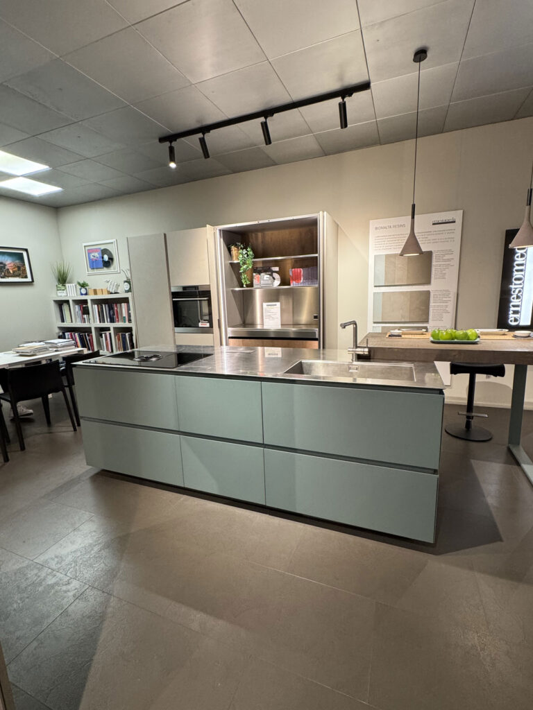 Cucina moderna con isola centrale "Cucina Obliqua", elettrodomestici da incasso e pensili aperti.