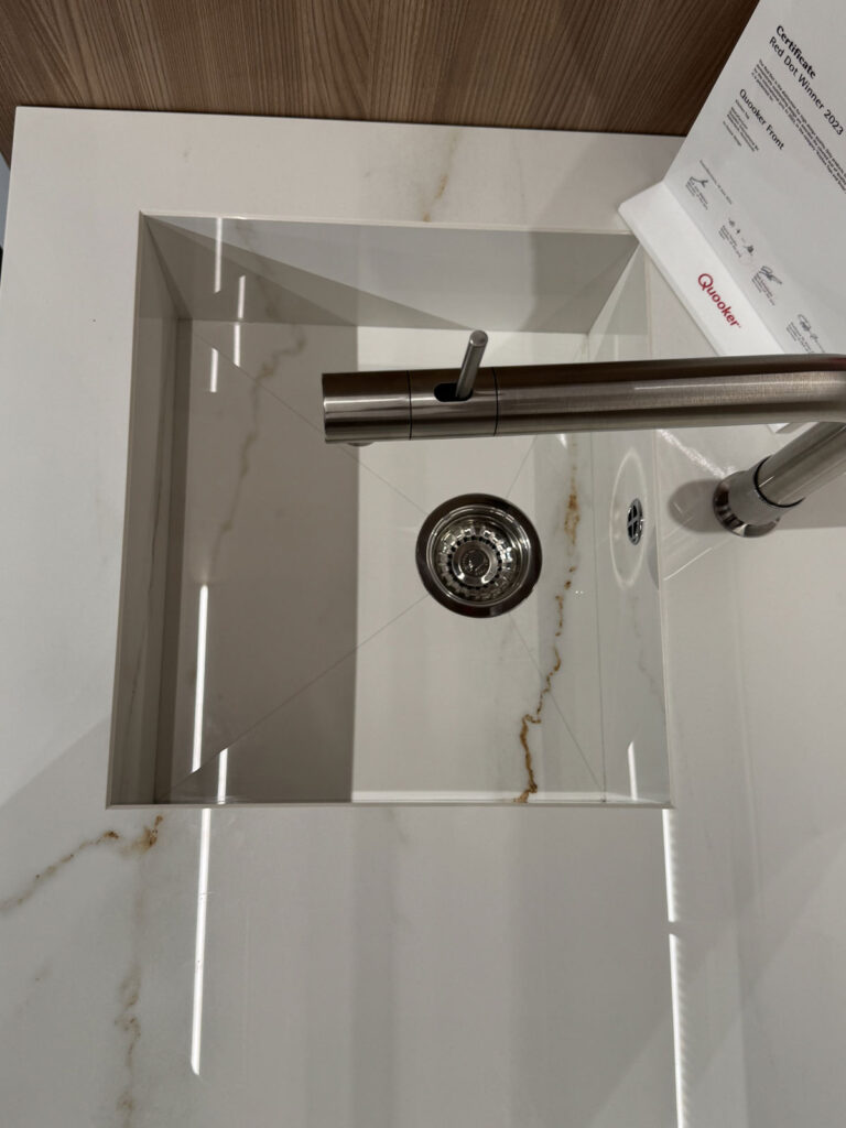 Lavello quadrato bianco con rubinetto in acciaio inossidabile su piano Ernestomeda in marmo beige, perfetto per le cucine moderne.