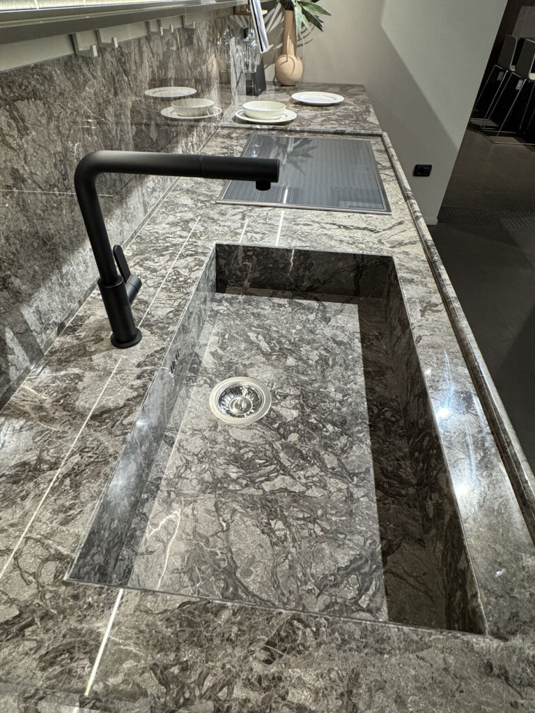 Piano cottura K-Lab Ernestomeda con lavello rettangolare in marmo, rubinetto nero opaco e piano cottura integrato.