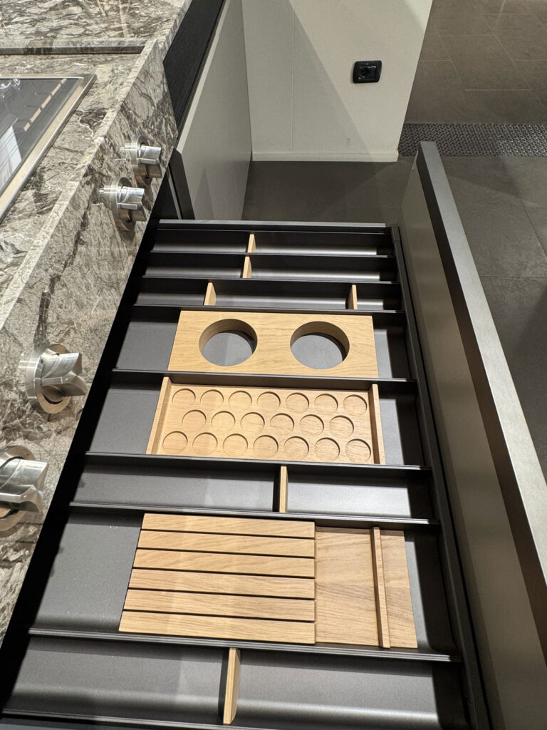 Cassetto da cucina Ernestomeda K-Lab con divisori in metallo nero e organizer in legno sotto il piano in pietra.
