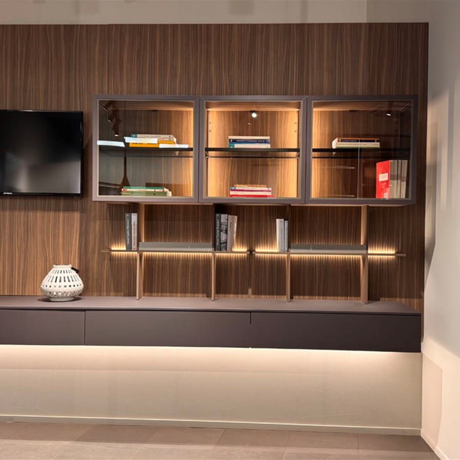 Parete attrezzata in legno con nicchie illuminate e madia sospesa in ambiente showroom