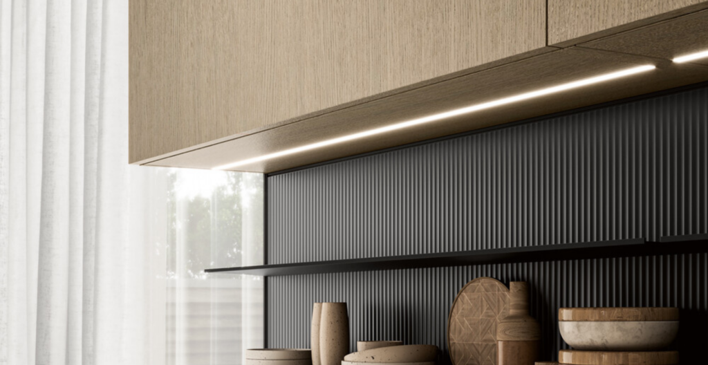 Cucina moderna con mobili in legno, pannello posteriore scuro a rilievo, luci a LED e mensola con ciotole e taglieri.