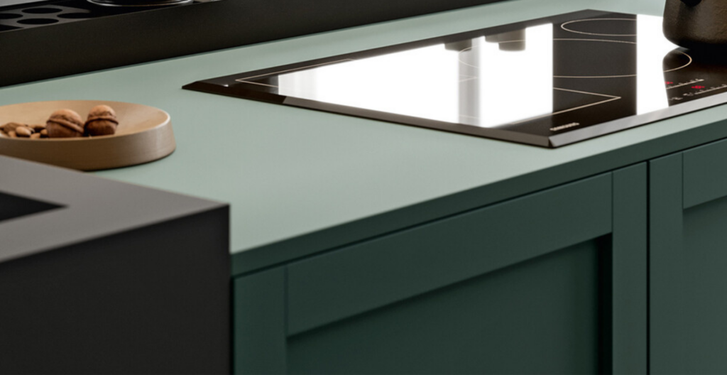 Top da cucina moderno con piano cottura integrato e mobili verdi, in stile minimalista ed elegante delle “Cucine Contemporanee”.