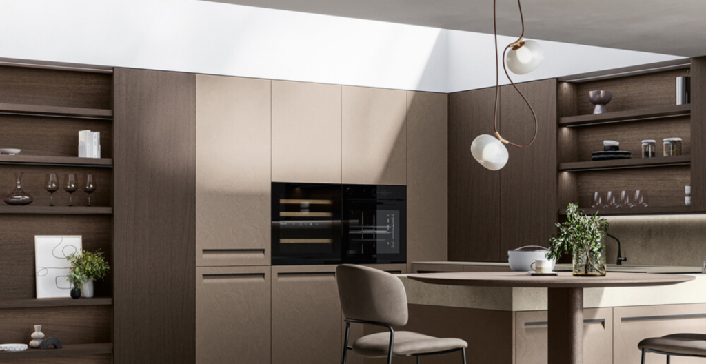 Cucina moderna con mobili in legno scuro, forno nero, tavolo rotondo e lampade a sospensione sotto la luce naturale.