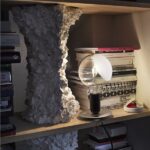 Libreria con ripiani illuminati, libri e oggetti decorativi