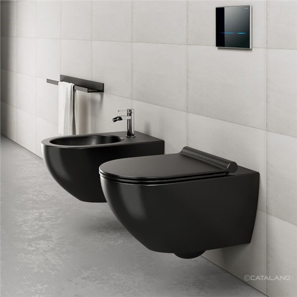 Vaso e bidet sospesi neri con placca di comando su parete chiara