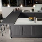 Cucina con isola scura, ante a telaio e tavolo integrato