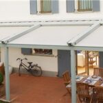 Pergotenda con copertura in tessuto sopra un patio con tavoli e biciclette