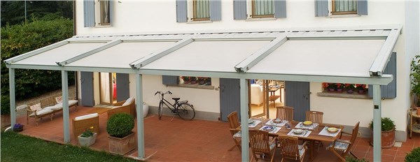 Pergotenda con copertura in tessuto sopra un patio con tavoli e biciclette