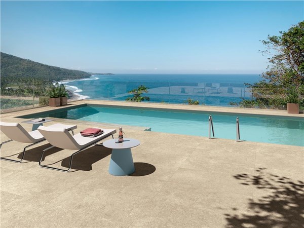 Bordo piscina in gres effetto pietra con lettini affacciati sul mare