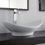 Lavabo ovale bianco d'appoggio su mensola scura con miscelatore cromato