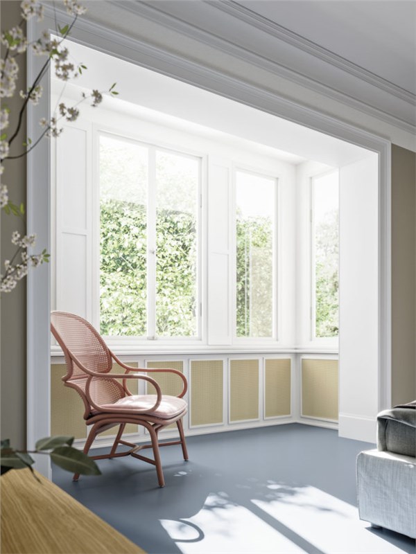 Bagno luminoso con finestre, poltrona in rattan e pavimento chiaro