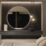 Bagno con grande specchio circolare retroilluminato e lavabo su mensola