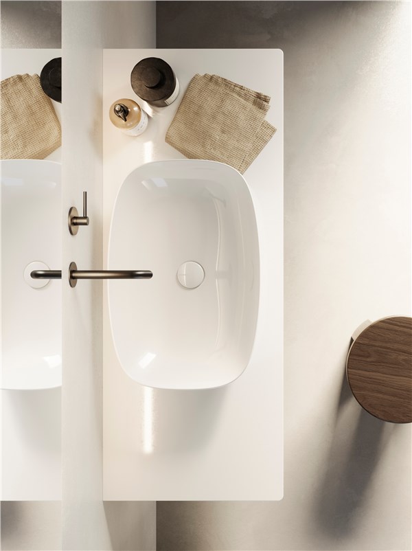 Lavabo integrato in un piano bianco visto dall'alto con accessori in legno