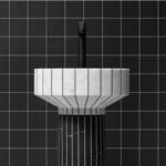 Lavabo a colonna scanalato su parete rivestita in mosaico nero