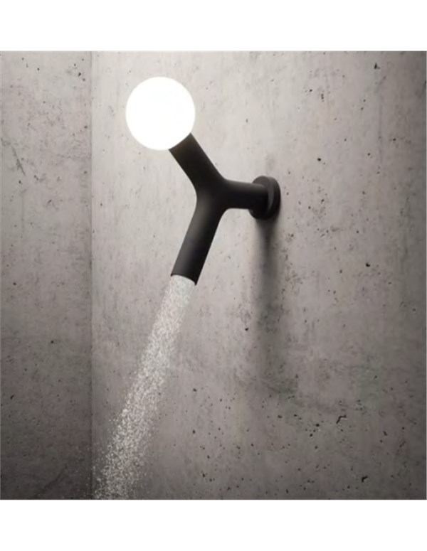 Lampada a parete a forma di rubinetto con sfera luminosa su fondo cemento