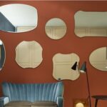 Parete color mattone con una composizione di specchi di forme diverse