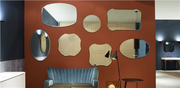 Parete color mattone con una composizione di specchi di forme diverse