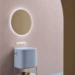 Mobile bagno azzurro su struttura metallica con specchio tondo e parete rosa