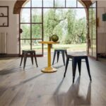 Ambiente rustico con pavimento in legno, vetrata ad arco e tavolini