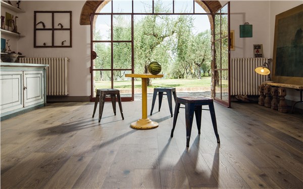Ambiente rustico con pavimento in legno, vetrata ad arco e tavolini