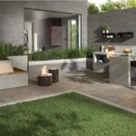 Patio con pavimento in gres effetto pietra, prato e zona pranzo coperta