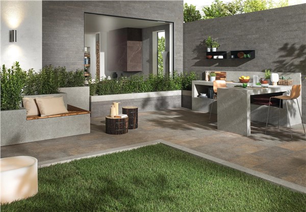 Patio con pavimento in gres effetto pietra, prato e zona pranzo coperta