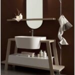 Bagno piccolo con specchio ovale illuminato, lavabo su consolle e parete scura