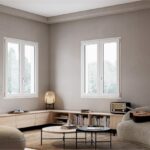 Salotto con due finestre, divano ad angolo e parete a doghe in legno