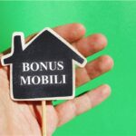 Mano che regge una sagoma di casa con la scritta bonus mobili su fondo verde