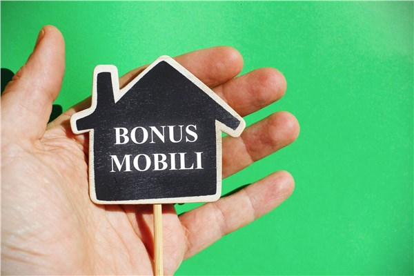 Mano che regge una sagoma di casa con la scritta bonus mobili su fondo verde