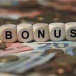 Cubi con la scritta bonus appoggiati su banconote e monete