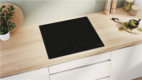 Piano cottura a induzione nero incassato in un top in legno chiaro
