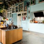 Cucina azzurra in stile industriale con cappa aspirante in acciaio e isola in legno
