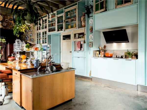Cucina azzurra in stile industriale con cappa aspirante in acciaio e isola in legno