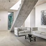 Loft industriale con pavimento chiaro di grande formato e divani in pelle