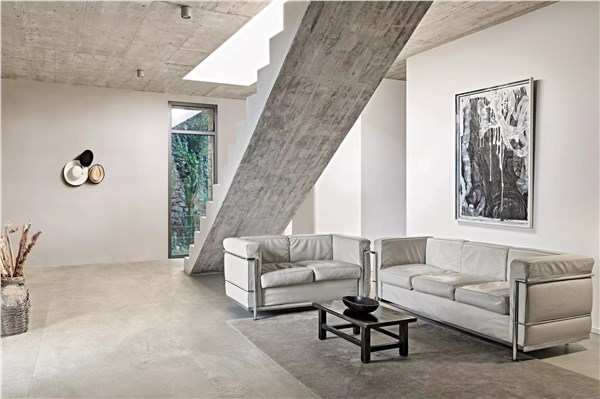 Loft industriale con pavimento chiaro di grande formato e divani in pelle
