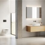 Bagno con lavabo d'appoggio su mobile in legno, sanitari e specchi illuminati