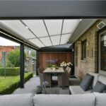 Veranda con copertura Corradi, divano da esterno e tavolo affacciata sul giardino