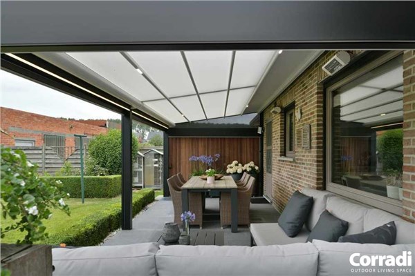 Veranda con copertura Corradi, divano da esterno e tavolo affacciata sul giardino