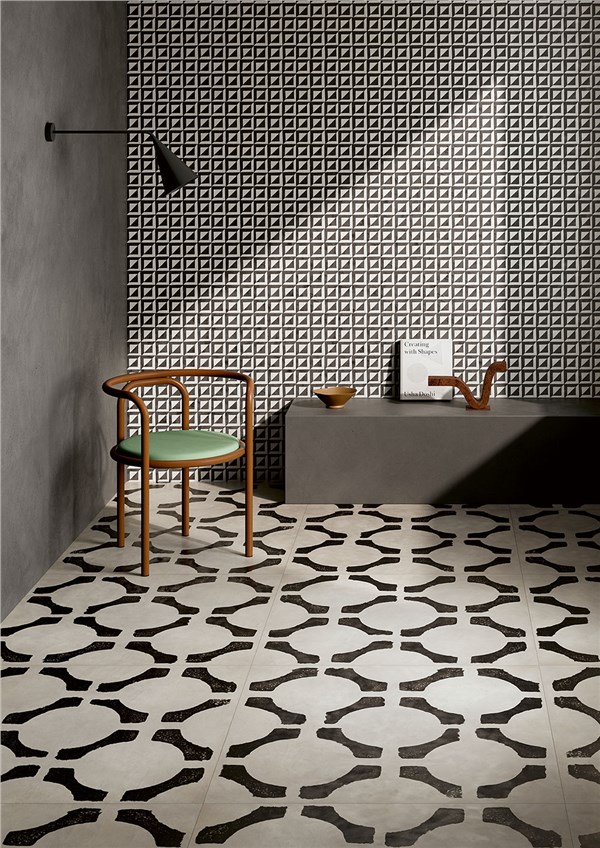 Ambiente con pavimento in cementine bianche e nere a motivo geometrico e parete a rilievo