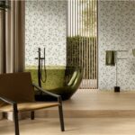 Bagno con parete decorata a motivo floreale, poltrona e lavabo a colonna
