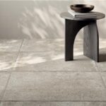 Pavimento in gres effetto pietra chiara con sgabello scuro e ombre