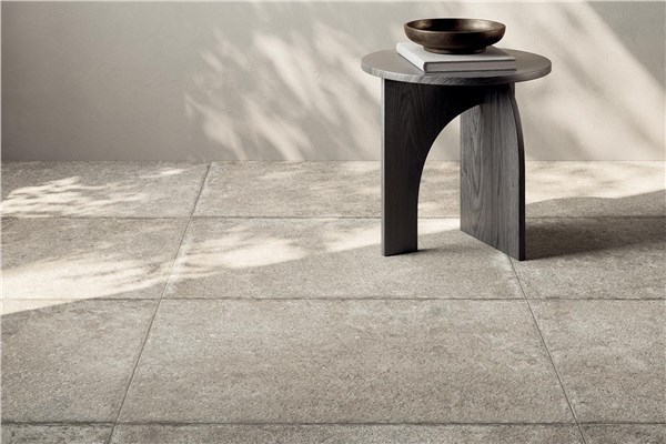 Pavimento in gres effetto pietra chiara con sgabello scuro e ombre