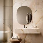 Bagno con parete in lastre effetto onice, lavabo sospeso e specchio ovale